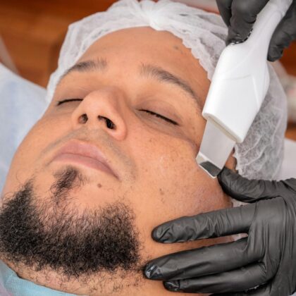 A man undergoing a facial treatment with advanced cosmetology equipment.