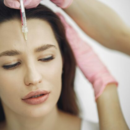 Close-up of facial treatment with injection in a spa setting, focusing on the forehead.